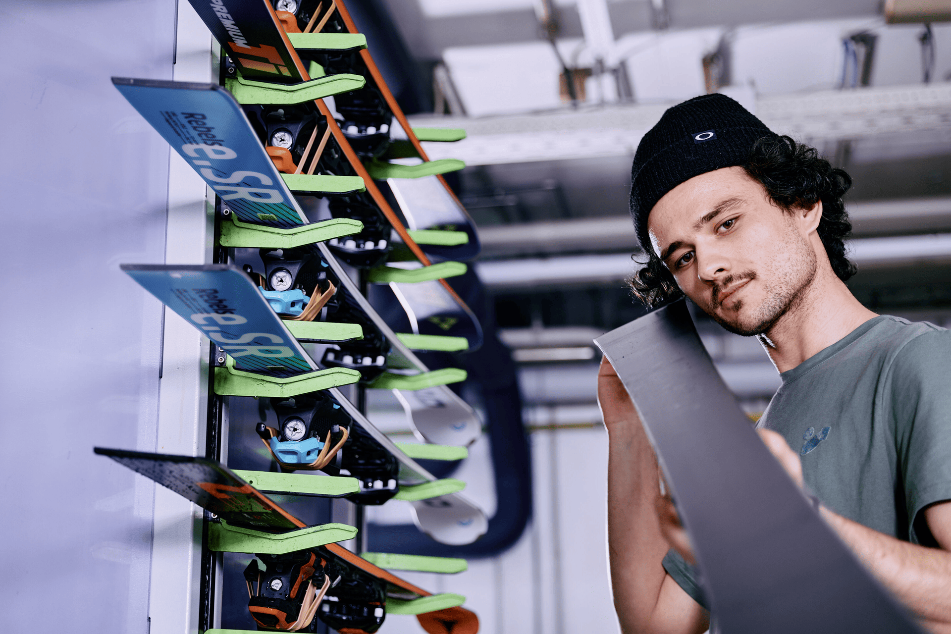 Ein geräumiger Skiraum mit weißen Schließfächern und Bänken. Eine Person sitzt da und passt ihre Skischuhe an. Die Skier lehnen an einem Schließfach und vermitteln eine ruhige, aufgeräumte Atmosphäre.