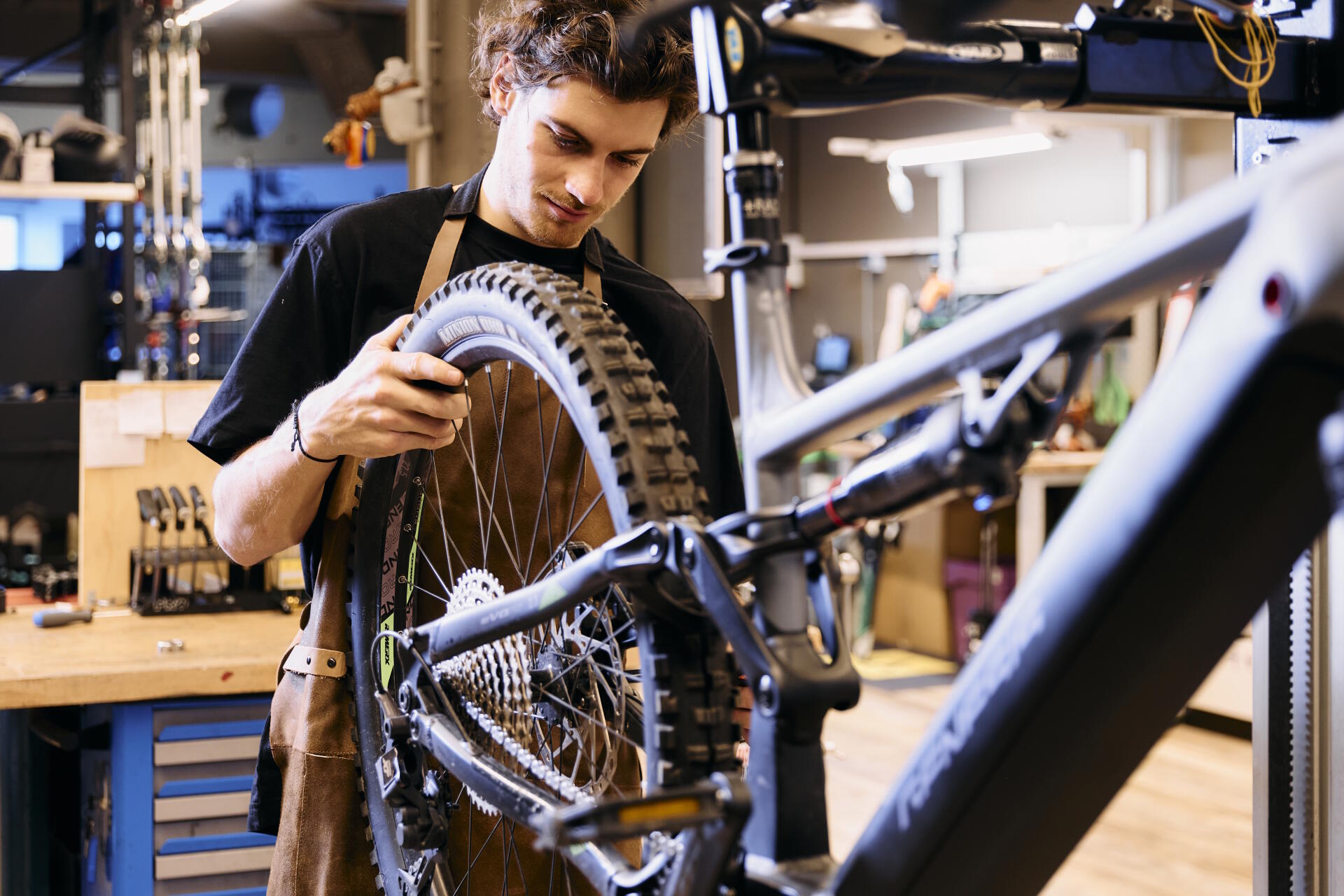 A bicycle mechanic inspects the rear wheel of a mountain bike in the workshop.
