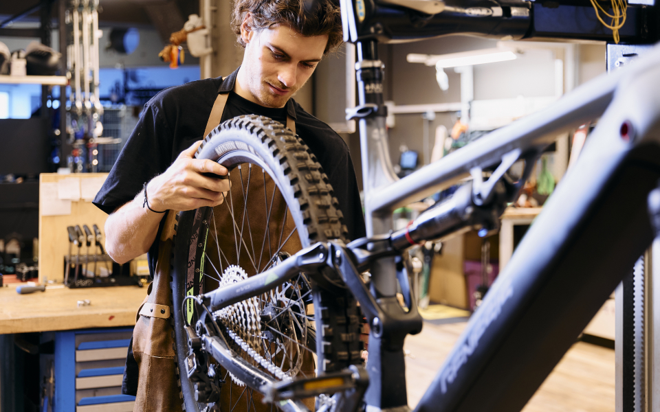 Ein gut beleuchtetes Bekleidungsgeschäft mit Regalen voller bunter Jacken, Hemden und Outdoor-Ausrüstung auf beiden Seiten. Der Raum wirkt aufgeräumt und einladend.
