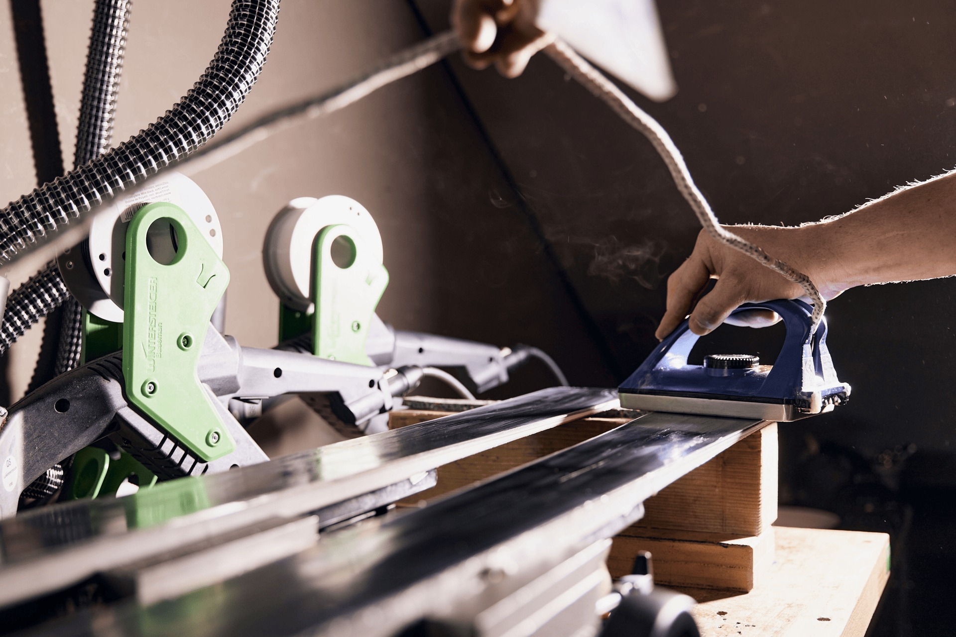 Nahaufnahme einer industriellen Maschine im Betrieb, mit Metallteilen, blauen Kabeln und Wassersprühnebel, die eine dynamische und technische Atmosphäre schaffen.